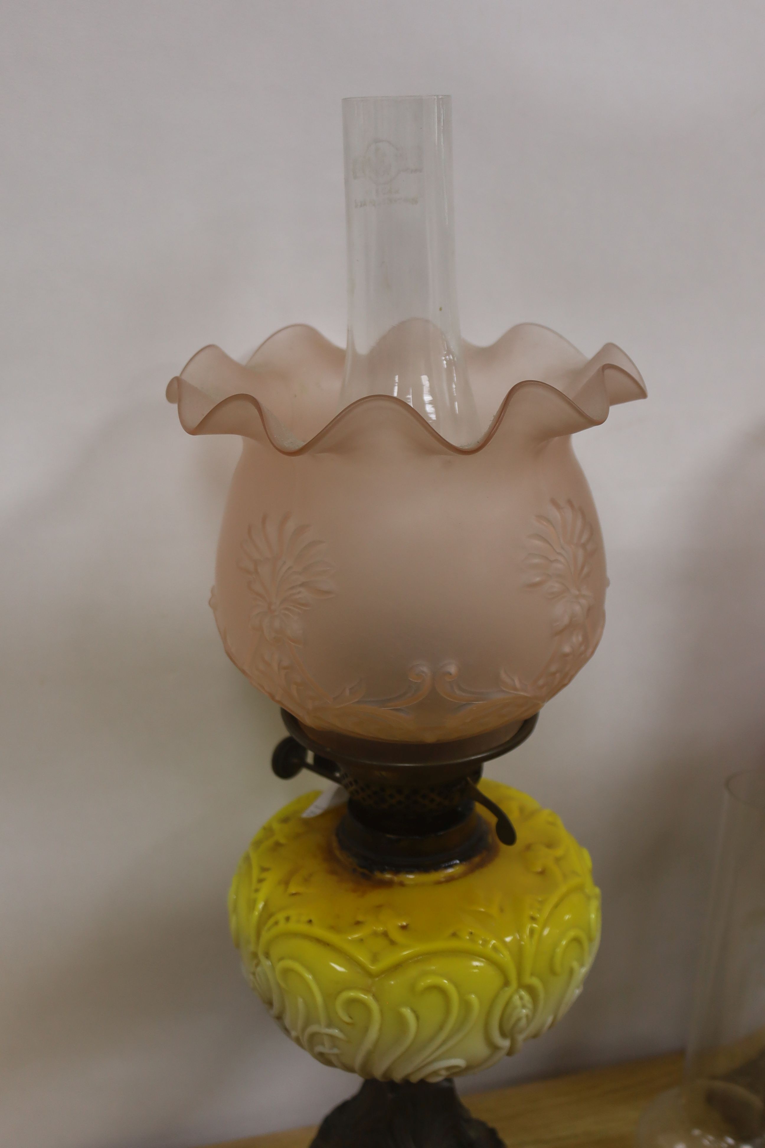Two late Victorian brass mounted oil lamps with pink and yellow tinted glass reservoirs, tallest 61 cm